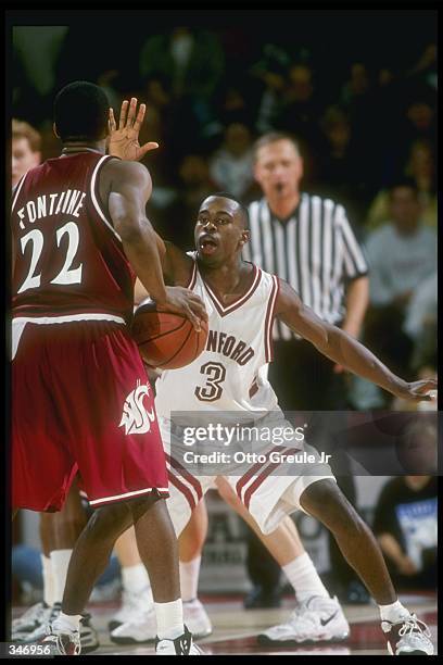 Guard Isaac Fontaine of the Washington State Cougars moves the ball as Stanford Cardinal guard Kris Weems covers him during a game at Maples Pavilion...
