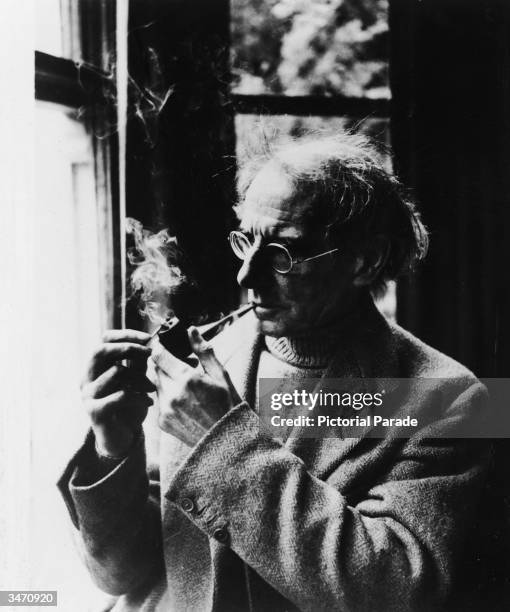 Portrait of Irish writer Sean O'Casey as he lights a pipe in front of a window, early 1950s.