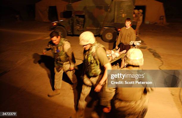 Navy medical corpsmen carry in a patient, as they treat US Marines with bullet wounds inflicted during an ambush by Iraqi insurgents east of the...
