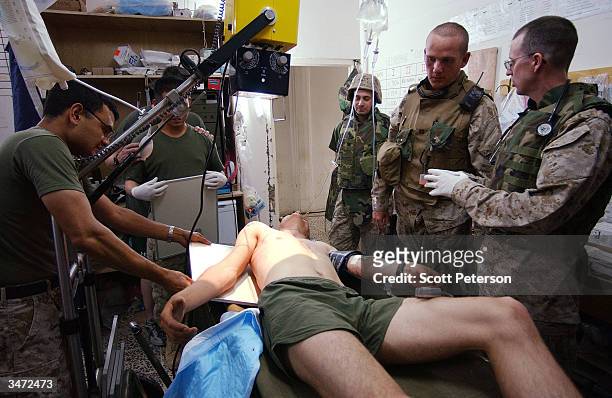 Navy medical corpsmen treat US Marines with bullet wounds inflicted during an ambush by Iraqi insurgents east of the encircled city of Fallujah, Iraq...