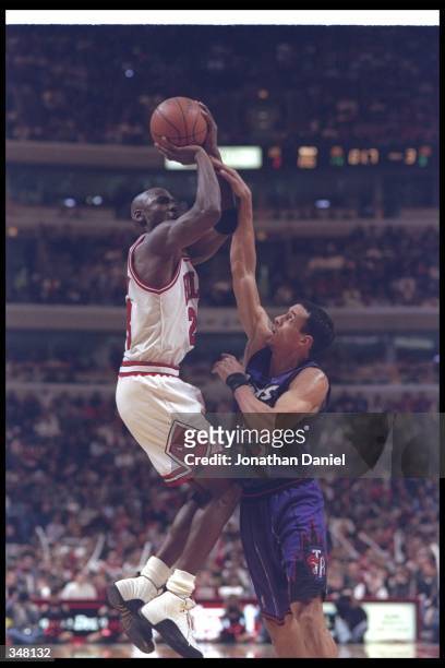 Guard Michael Jordan of the Chicago Bulls takes a shot as Toronto Raptors guard Doug Christie covers him during a game at the United Center in...
