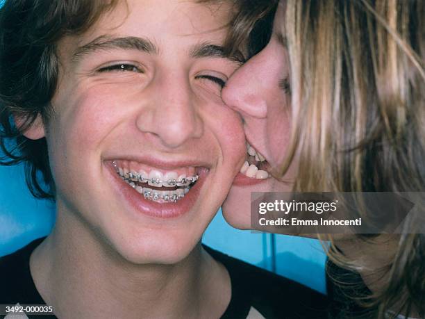 girl biting boys cheek - boys with braces stock pictures, royalty-free photos & images