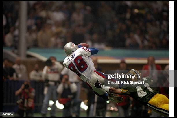 Wide receiver Terry Glenn of the New England Patriots catches the ball as Green Bay Packers defensive back Eugene Robinson tackles him during Super...