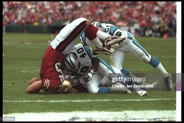 Tight end Ted Popson of the san Francisco 49ers gets tackled by Carolina Panthers linebacker Sam Mills and safety Pat Terrell during a game at 3Com...