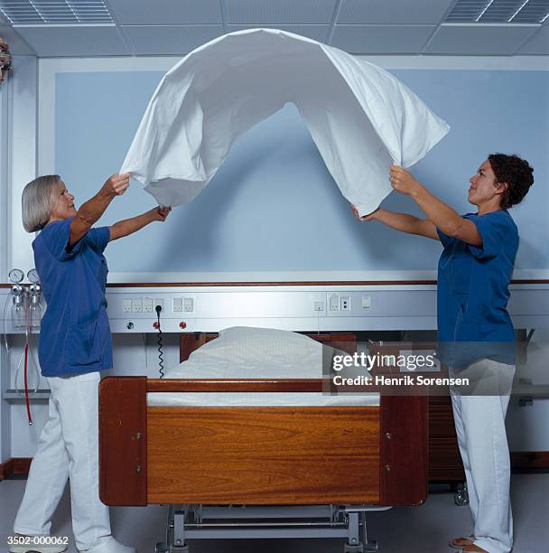 nurses changing hospital bed - bett machen stock-fotos und bilder