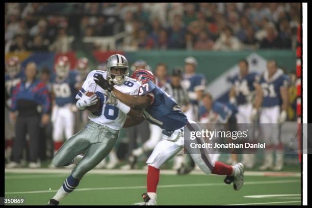 Wide receiver Michael Irvin of the Dallas Cowboys moves the ball as Buffalo Bills defensive back Nate Odomes attempts to tackle him during Super Bowl...