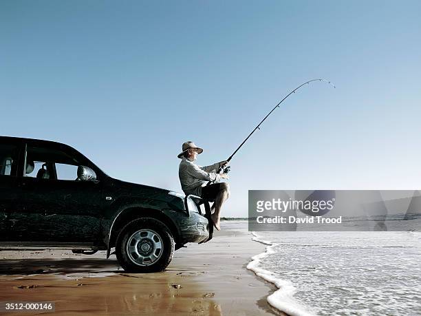 elderly man fishing in ocean - fischen stock-fotos und bilder