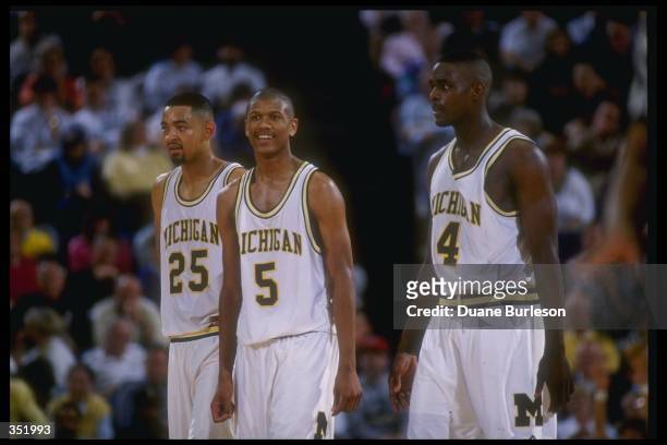 Michigan Wolverines forward Juwan Howard, guard Jalen Rose, and forward Chris Webber look on during a game against the Indiana Pacers.