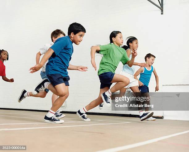 children running in gymnasium - school sports stock-fotos und bilder