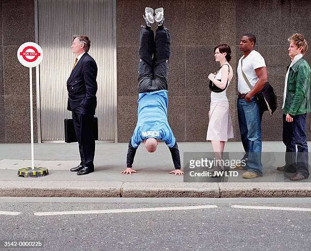 man doing handstand in queue - bizarre foto e immagini stock