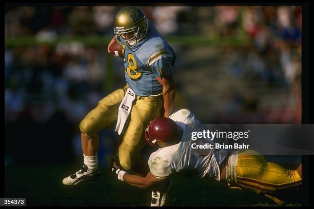 Quarterback Cade McNown of the UCLA Bruins runs with the ball as USC Trojans linebacker Sammy Knight attempts to tackle him during a game at the Rose...