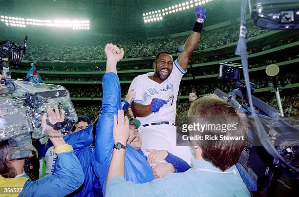 Joe Carter of the Toronto Blue Jays is held aloft after hitting a three-run homer in the bottom of the ninth to win the World Series, four games to...
