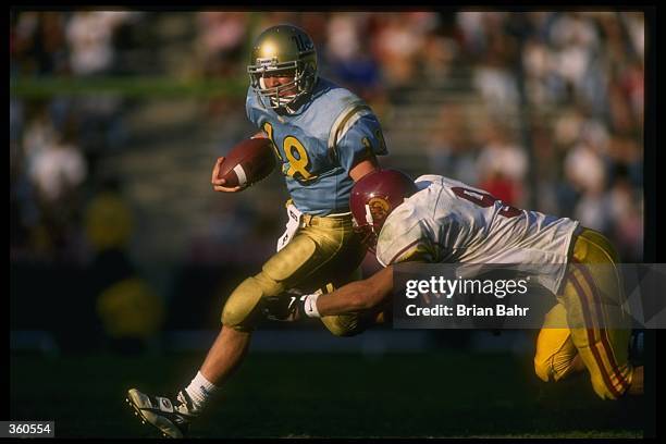 Quarterback Cade McNown of the UCLA Bruins attempts to avoid the tackle of USC Trojans linebacker Sammy Knight during a game at the Rose Bowl in...