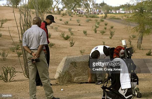 Tiger Woods with his caddie Fluff look at a boulder which is in the way during the Phoenix Open at the TPC of Scottsdale in Scottsdale, Arizona.