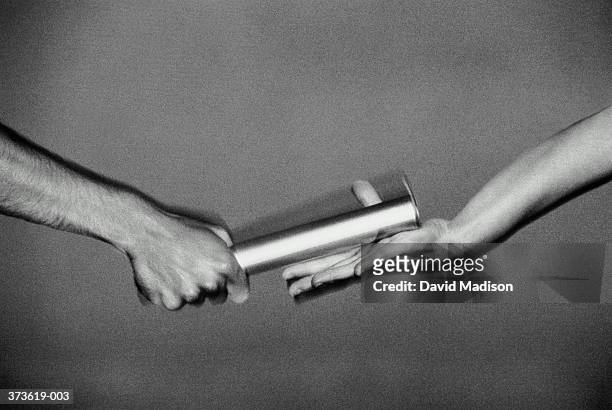 hands passing relay baton, close-up (blurred motion, b&w) - passing sport stock pictures, royalty-free photos & images