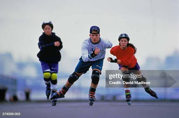 three teenagers (16-18) in-line skating, front view - patín en línea fotografías e imágenes de stock