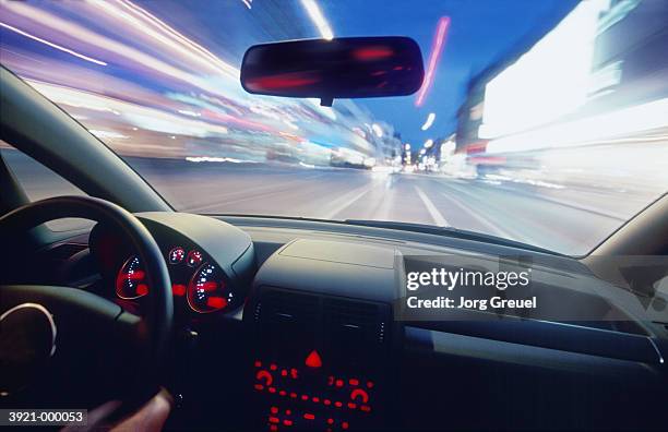 city at night from moving car - steering wheel foto e immagini stock