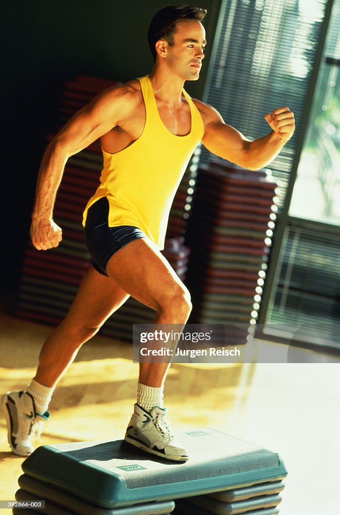 Young man doing step aerobics in sports hall