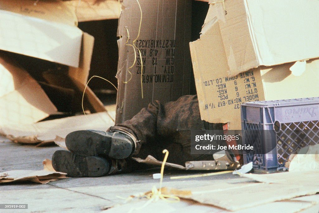 Feet of homeless person sleeping in cardboard box