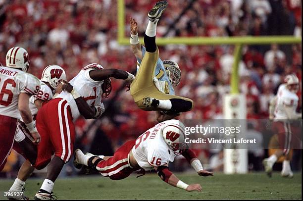 Cade McNown of the UCLA Bruins is tripped during the Rose Bowl Game against the Wisconsin Badgers at the Rose Bowl in Pasadena, California. The...