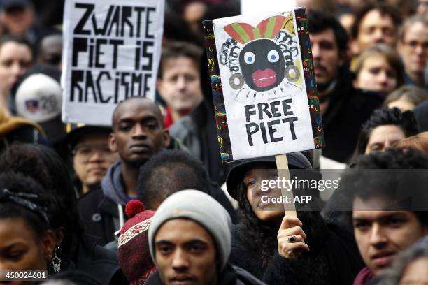 Demonstrators hold signs reading "Black Pete is Rascism" and "Free Black Pete" during a demonstration against Zwarte Piet in Amsterdam, on November...