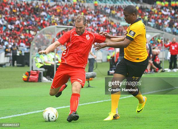 In this handout image provided by the ITM Group, Jason McAteer of Liverpool FC Legends tries to hold off Abel Shongwe of Kaizer Chiefs Legends during...