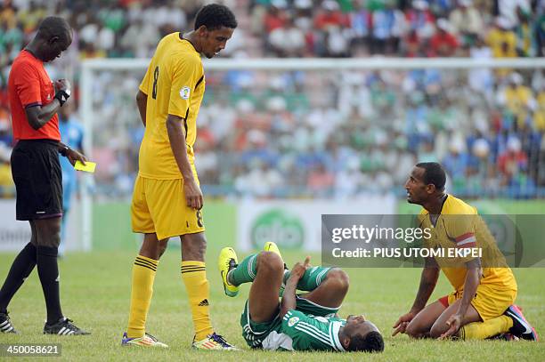 Ethiopia's Girma Adane kneels on the ground as Gambian referee Bakary Gassama prepares a yellow card for a foul on Nigerian midfielder Mikel Obi...