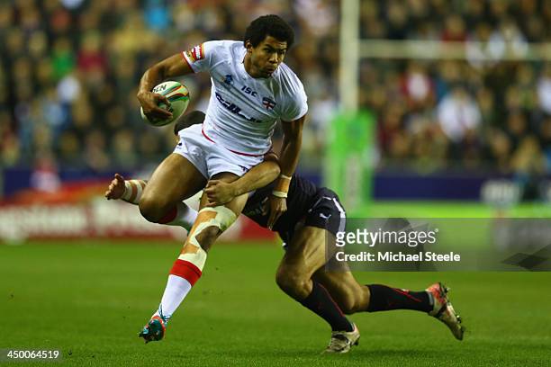 Kallum Watkins of England barges through the challenge of Sebastian Raguin of France during the Rugby League World Cup Quarter Final match between...