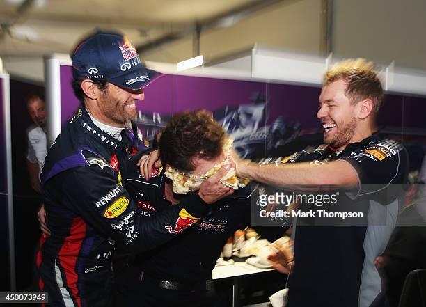 Sebastian Vettel of Germany and Infiniti Red Bull Racing and Mark Webber of Australia and Infiniti Red Bull Racing push a cake into the face of their...