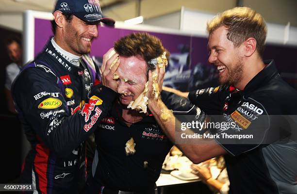 Sebastian Vettel of Germany and Infiniti Red Bull Racing and Mark Webber of Australia and Infiniti Red Bull Racing push a cake into the face of their...