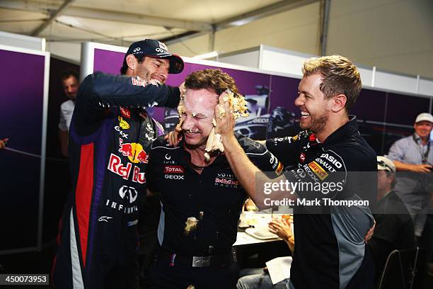 Sebastian Vettel of Germany and Infiniti Red Bull Racing and Mark Webber of Australia and Infiniti Red Bull Racing push a cake into the face of their...