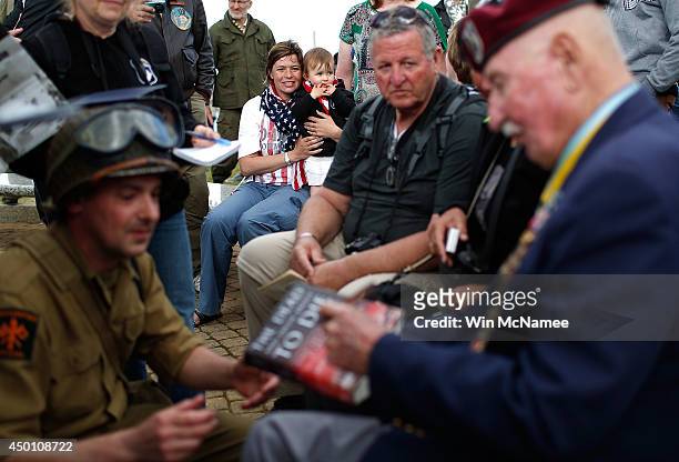 Local residents watch as Sgt. Major Retired Bill Ryan, who landed at Omaha Beach 70 years ago tomorrow, signs autographs following a ceremony...