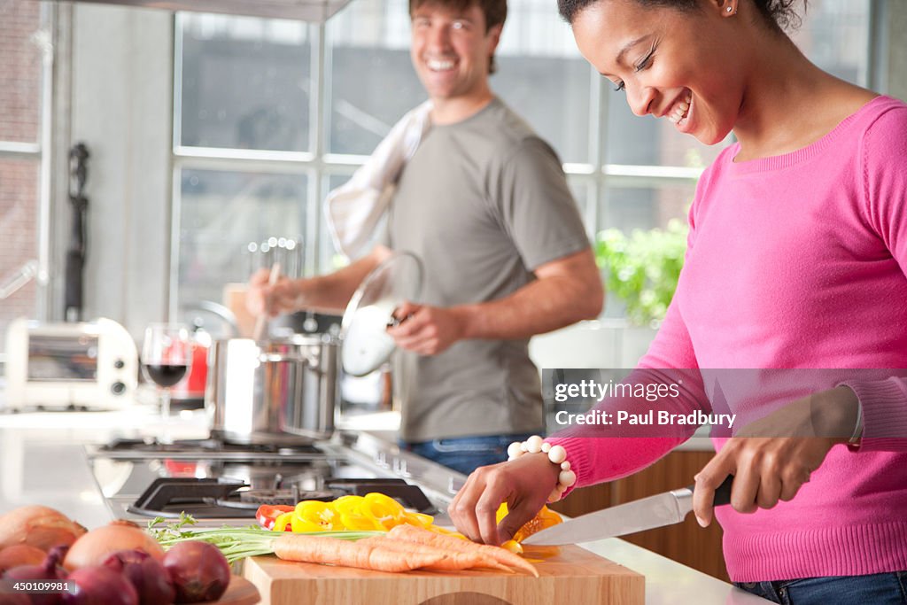 Woman cutting yellow peppers with man in background