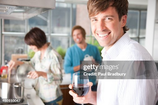 Three people in kitchen with wine Three people in kitchen with wine