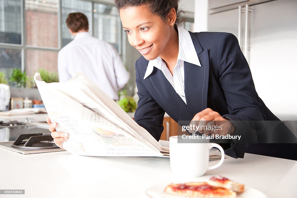 Woman with toast and man in background pouring coffee