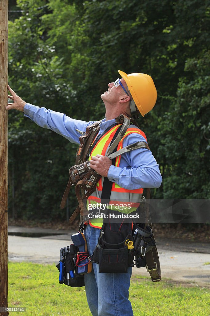 Communications engineer preparing to climb pole