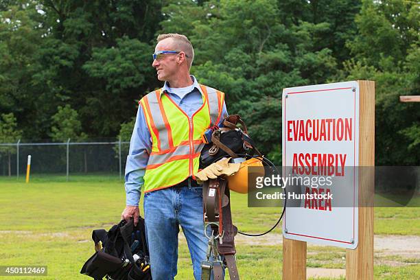 communications engineer with climbing equipment and tool belts at evacuation assembly area - workplace evacuation stock pictures, royalty-free photos & images