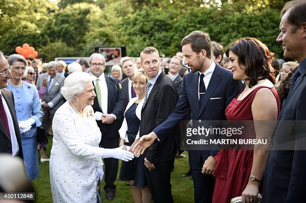 Britain's Queen Elizabeth II flanked by Britain Ambassador to France, Sir Peter Ricketts shakes hands with Sir Bradley Wiggins, winner of the 2012...