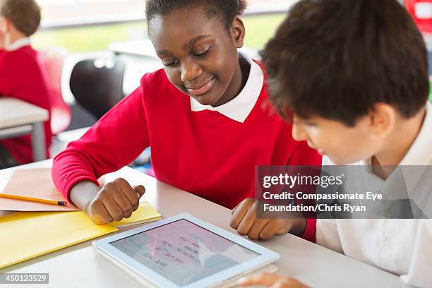 students sharing digital tablet in classroom - children on a tablet stock pictures, royalty-free photos & images