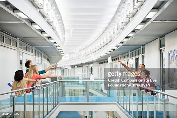 college students throwing paper in hallway - ballustrade stockfoto's en -beelden