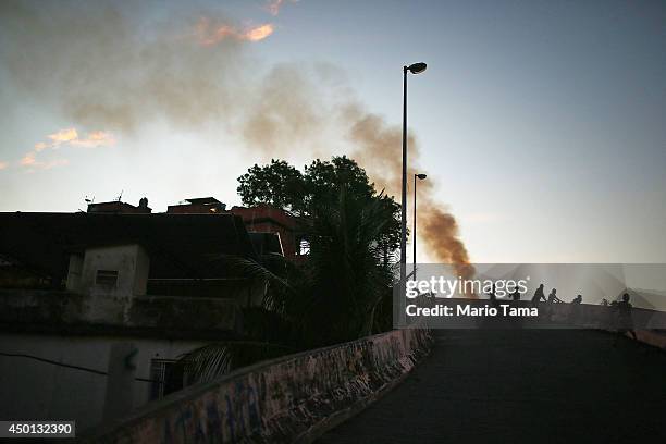 Kids look over a ledge as a trash fire burns in the Mangueira community, or 'favela', which overlooks the famed Maracana Stadium on June 5, 2014 in...