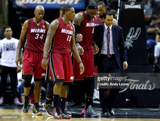 LeBron James of the Miami Heat is helped off the court after cramping up against the San Antonio Spurs during Game One of the 2014 NBA Finals at the...