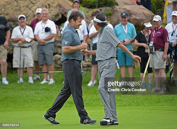 Nick Faldo of England and Eduardo Romero of Argentina celebrate a birdie on the first hole during the first round of the Big Cedar Lodge Legends of...