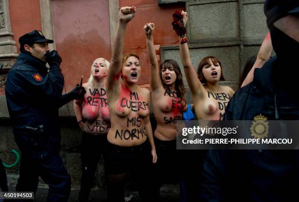 Shouting bare-breasted activists of feminist movement Femen are surrounded by policemen during an anti-abortion march in Madrid on November 17, 2013....