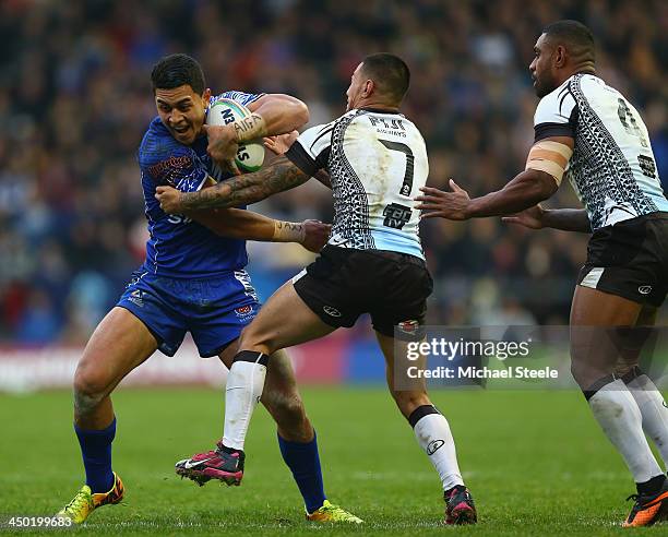 Tim Lafai of Samoa is held up by Aaron Groom and Waisale Ligani Naiqama of Fiji during the Rugby League World Cup Quarter Final match between Samoa...