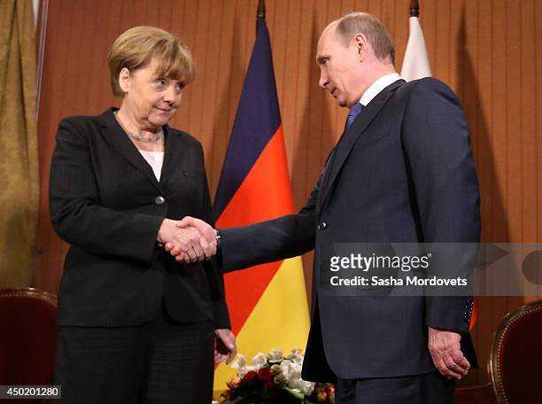 President Vladimir Putin of Russia shakes hands with Chancellor Angela Merkel of Germany during their meeting in the Barriere Normandy Hotel on June...