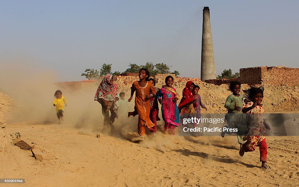 Pakistani children enjoy playing near a garbage dump site at...