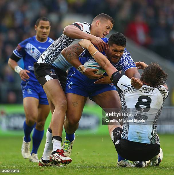 Mose Masoe of Samoa is held up by Kane Evans and Ashton Sims of Fiji during the Rugby League World Cup Quarter Final match between Samoa and Fiji at...
