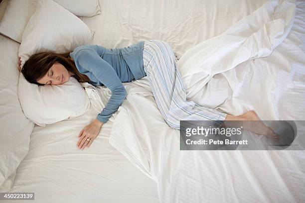 middle aged woman sleeping in bed - brunette woman bed stockfoto's en -beelden