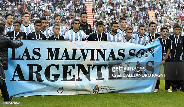 Argentina's footballers pose for photographers holding a banner reading "The Malvinas / Falkland Islands are Argentine" before a friendly football...